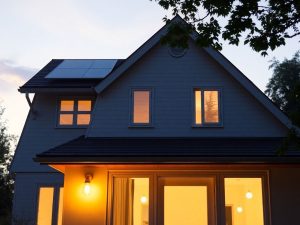 Casă modernă cu panouri solare și lumini LED aprinse.
